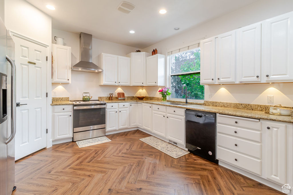 Kitchen with electric stove, wall chimney exhaust hood, a sink, dishwasher, and recessed lighting