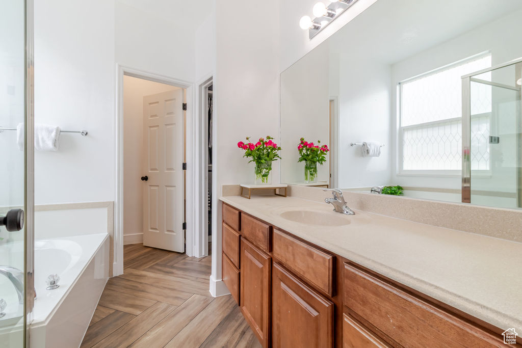Full bath with a stall shower, vanity, and a bath