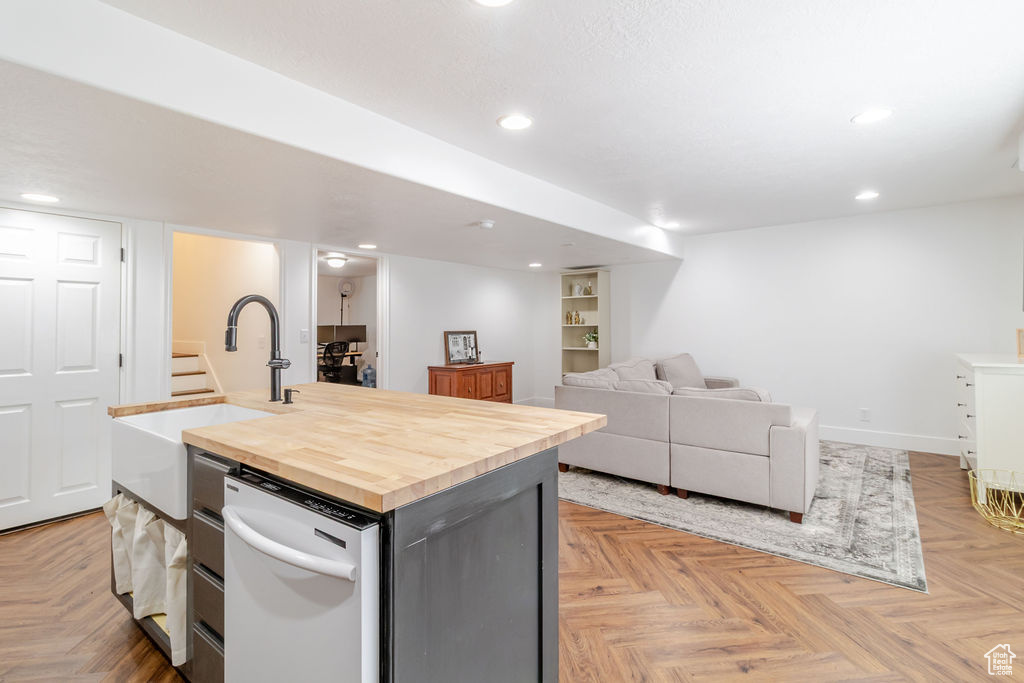 Kitchen featuring a kitchen island with sink, white dishwasher, butcher block counters, open floor plan, and recessed lighting