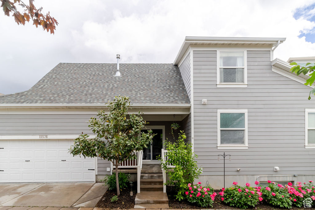 View of front of house featuring concrete driveway, a porch, roof with shingles, and a garage