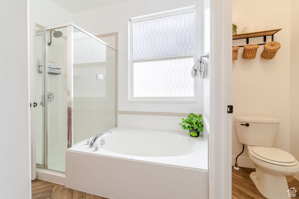Full bath with wood finished floors, a shower stall, a garden tub, and toilet