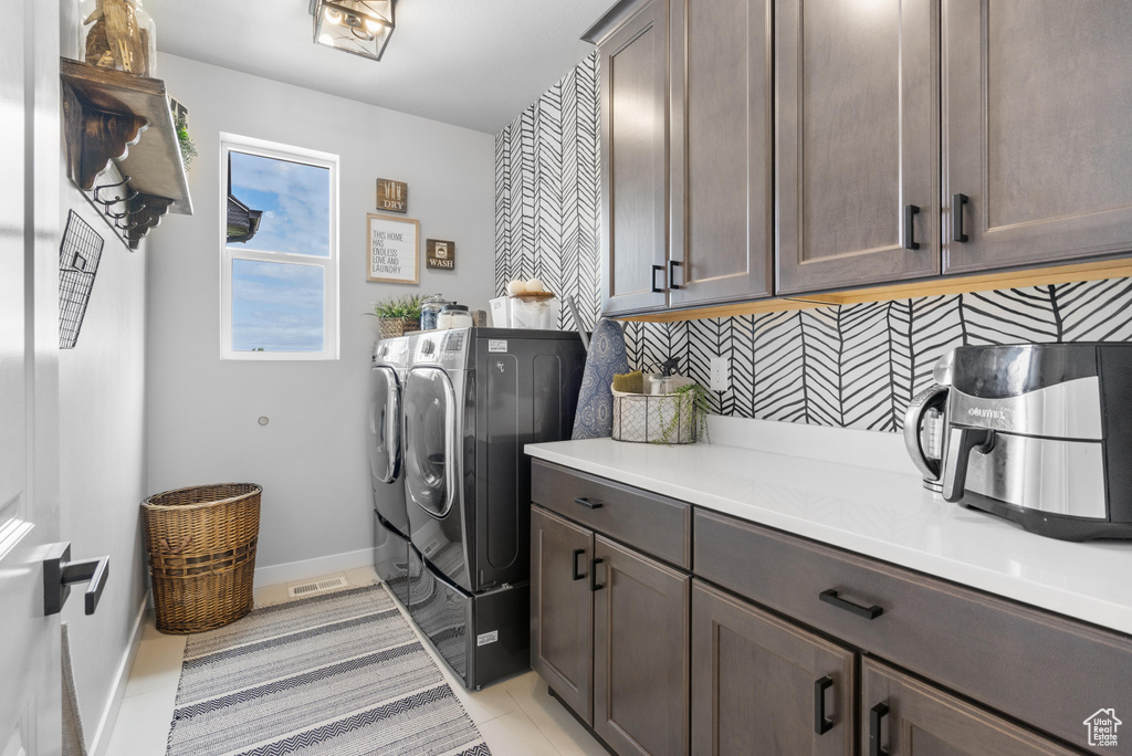Laundry room with washer and dryer, cabinet space, baseboards, and light tile patterned floors