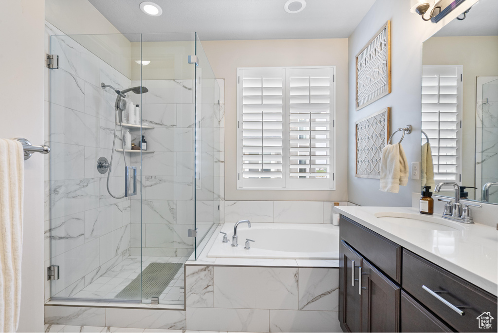 Bathroom featuring healthy amount of natural light, a marble finish shower, a garden tub, vanity, and recessed lighting