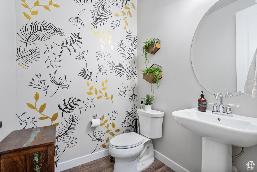 Bathroom featuring wood finished floors, baseboards, toilet, and a sink