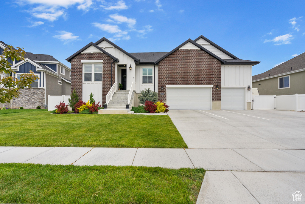 View of front of home with driveway, brick siding, and board and batten siding