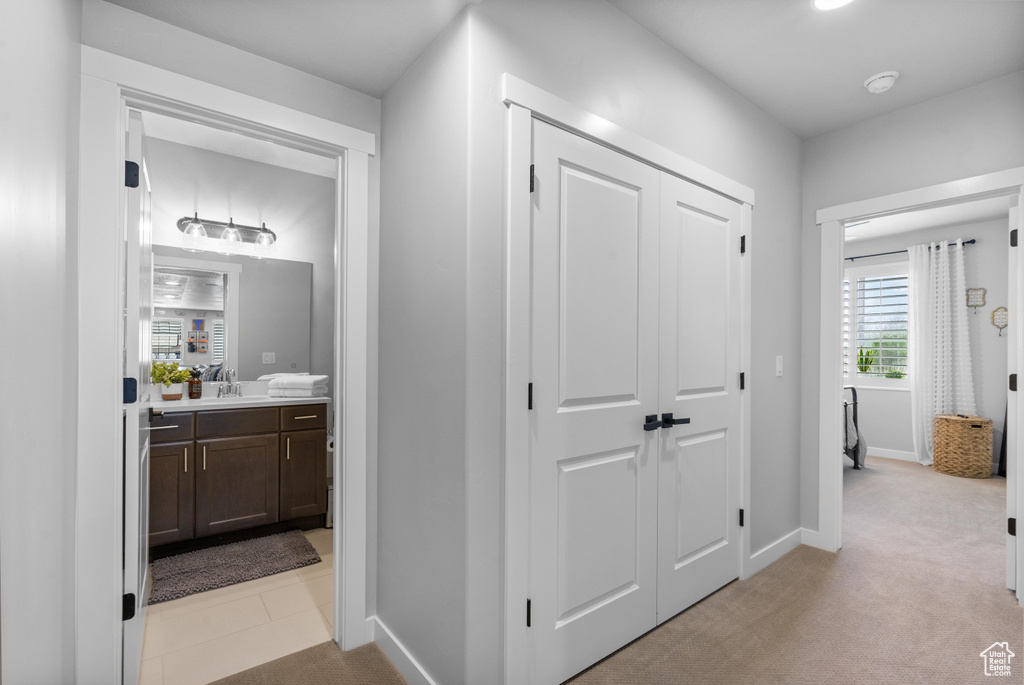 Corridor with a sink, baseboards, and light carpet