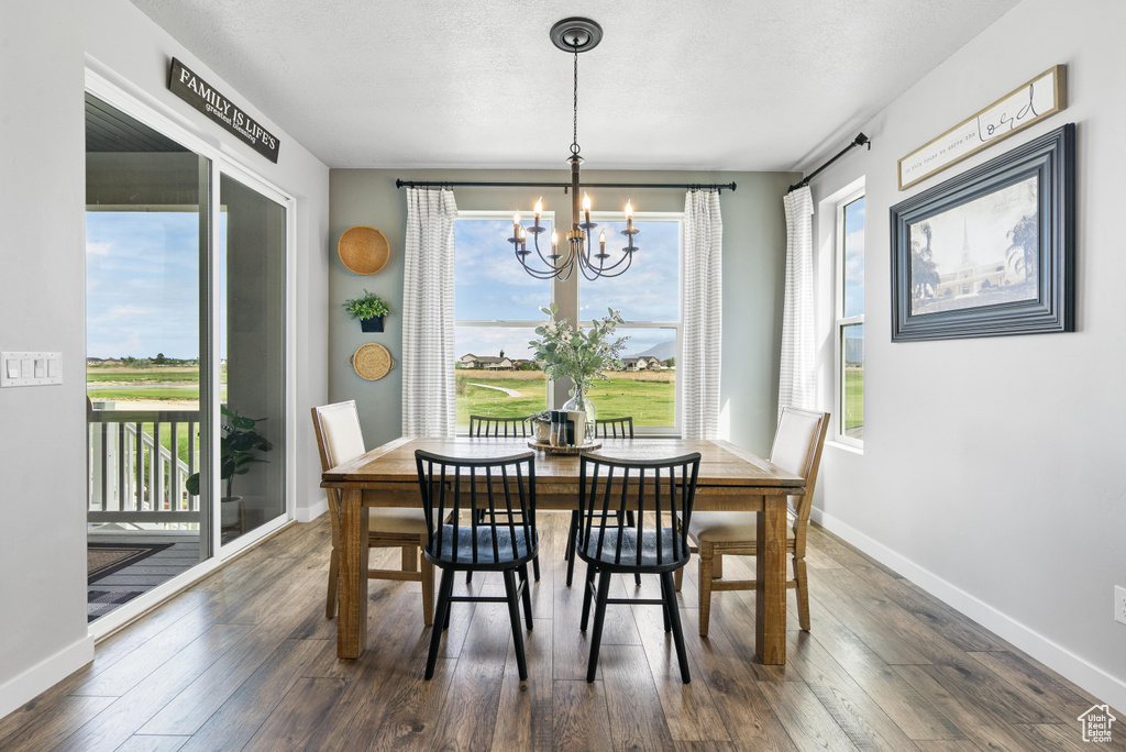 Dining area featuring a chandelier, dark wood-style flooring, and healthy amount of natural light