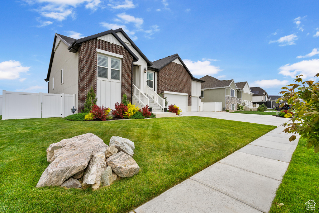 View of front of home with brick siding, concrete driveway, a residential view, a gate, and an attached garage