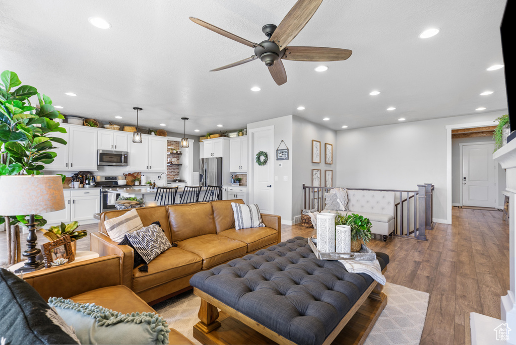 Living area featuring a ceiling fan, recessed lighting, baseboards, and light wood finished floors