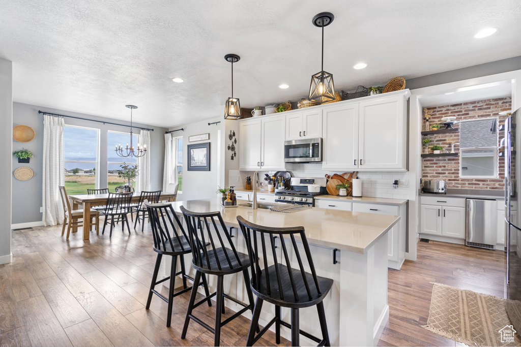 Kitchen with stainless steel appliances, backsplash, light wood-style floors, a chandelier, and recessed lighting