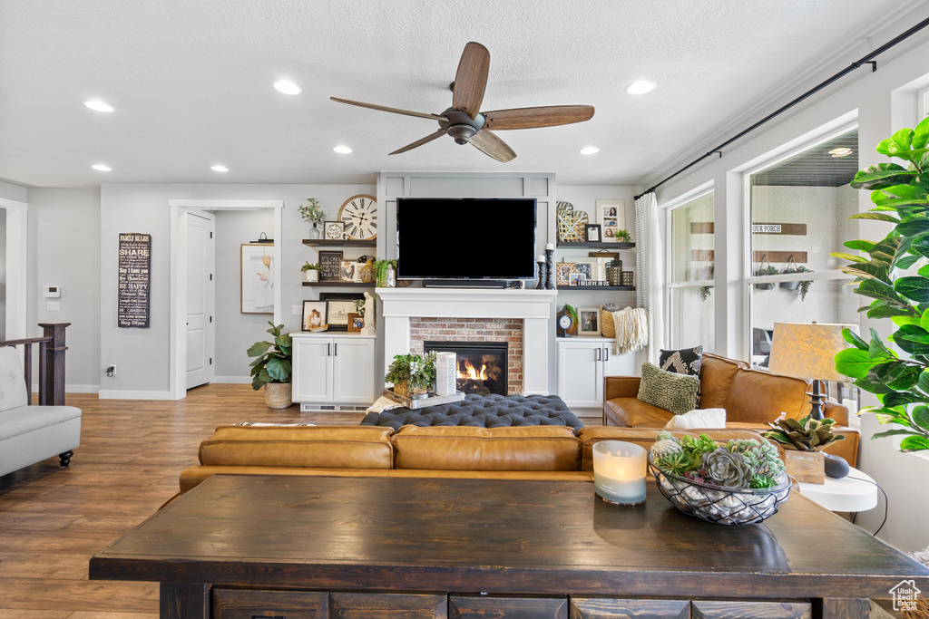 Living area with a ceiling fan, a brick fireplace, light wood-style floors, recessed lighting, and baseboards