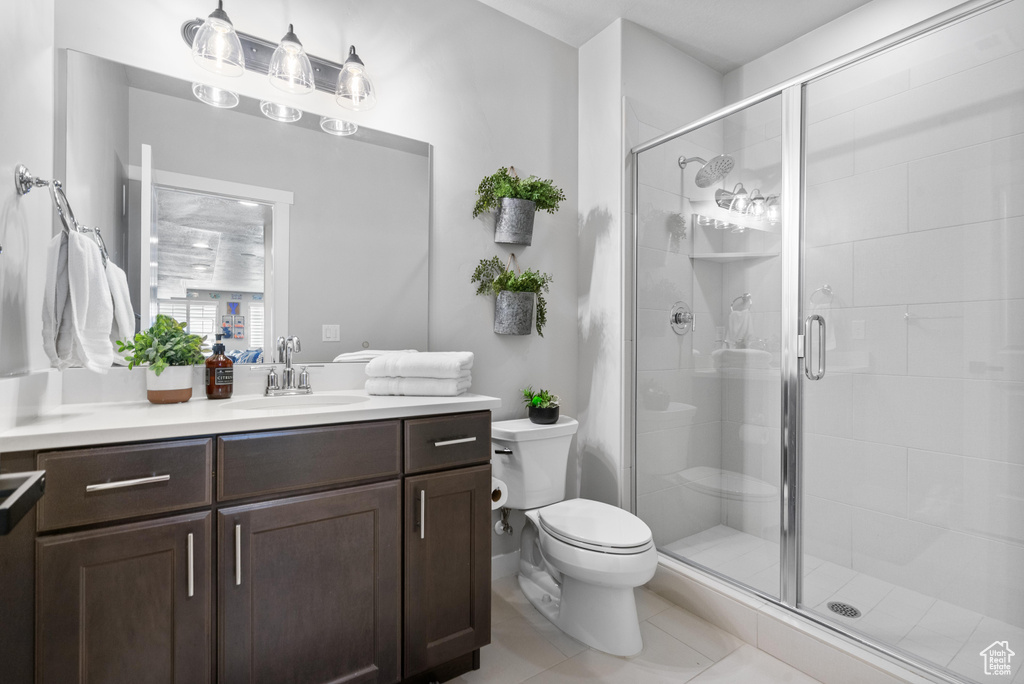 Full bathroom with toilet, a stall shower, vanity, and tile patterned flooring