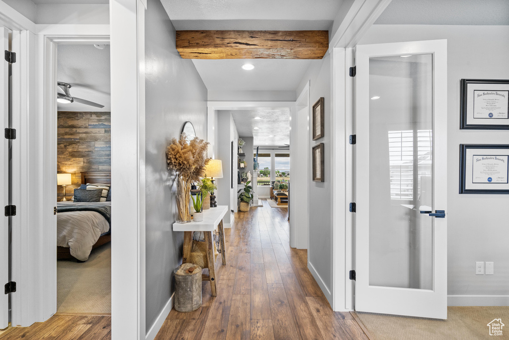 Hallway with beamed ceiling, hardwood / wood-style floors, baseboards, and recessed lighting