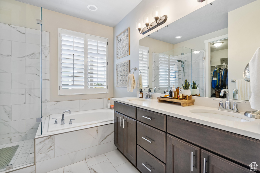 Bathroom featuring a shower stall, marble finish floors, a garden tub, double vanity, and a walk in closet