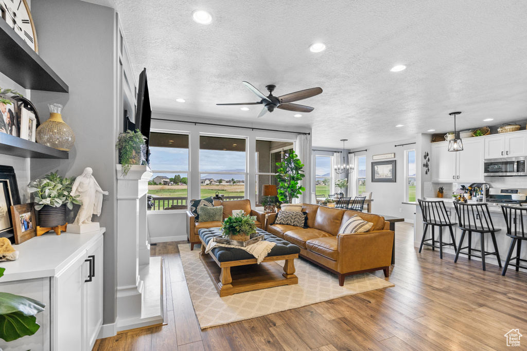 Living area with ceiling fan, light wood finished floors, recessed lighting, a textured ceiling, and a fireplace