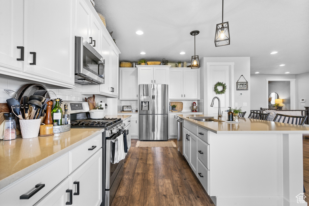 Kitchen featuring appliances with stainless steel finishes, a sink, recessed lighting, pendant lighting, and tasteful backsplash