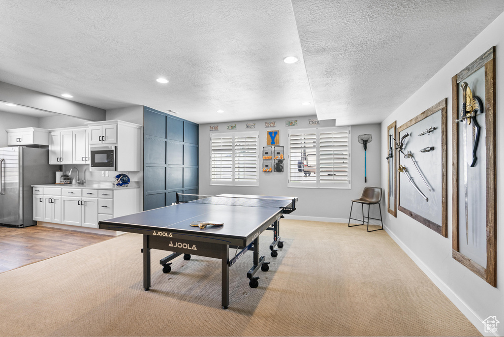 Game room with light carpet, a textured ceiling, baseboards, recessed lighting, and a sink