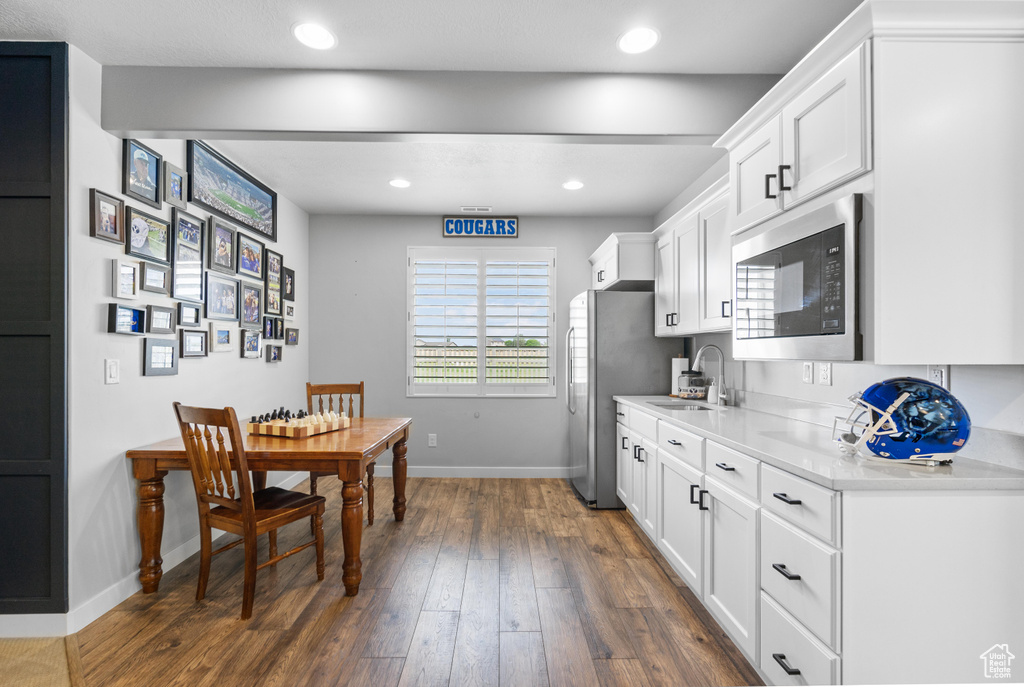 Kitchen with built in microwave, baseboards, light countertops, a sink, and white cabinets