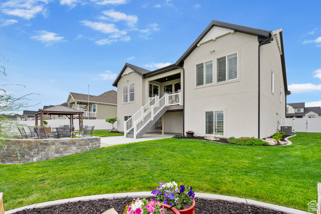 Back of house featuring a gazebo, a patio area, stucco siding, stairs, and central AC