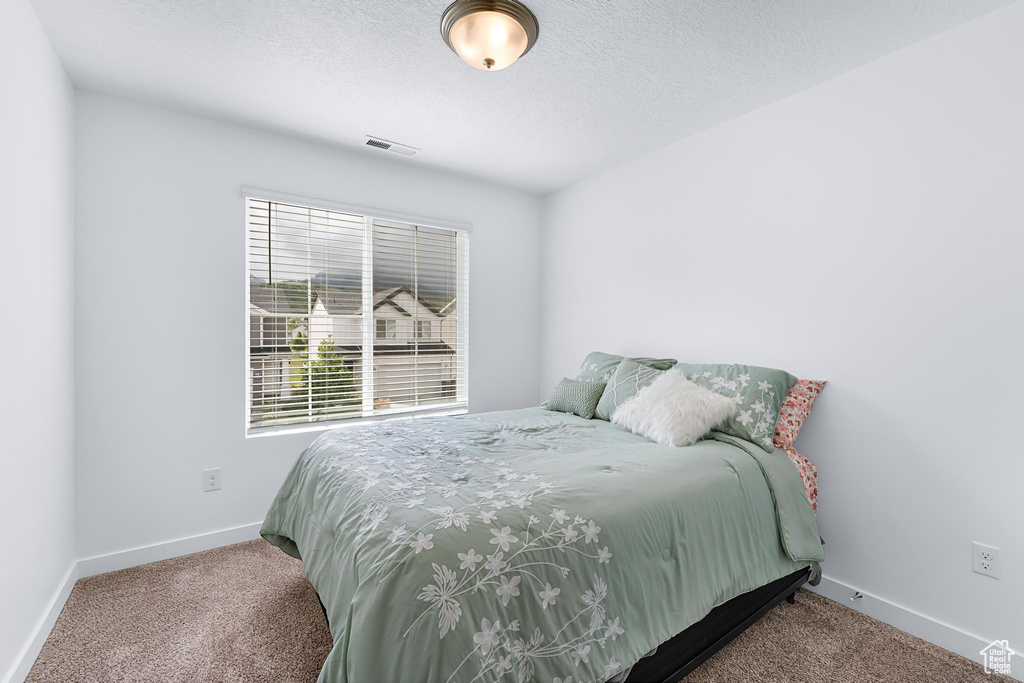Bedroom with carpet, baseboards, and a textured ceiling