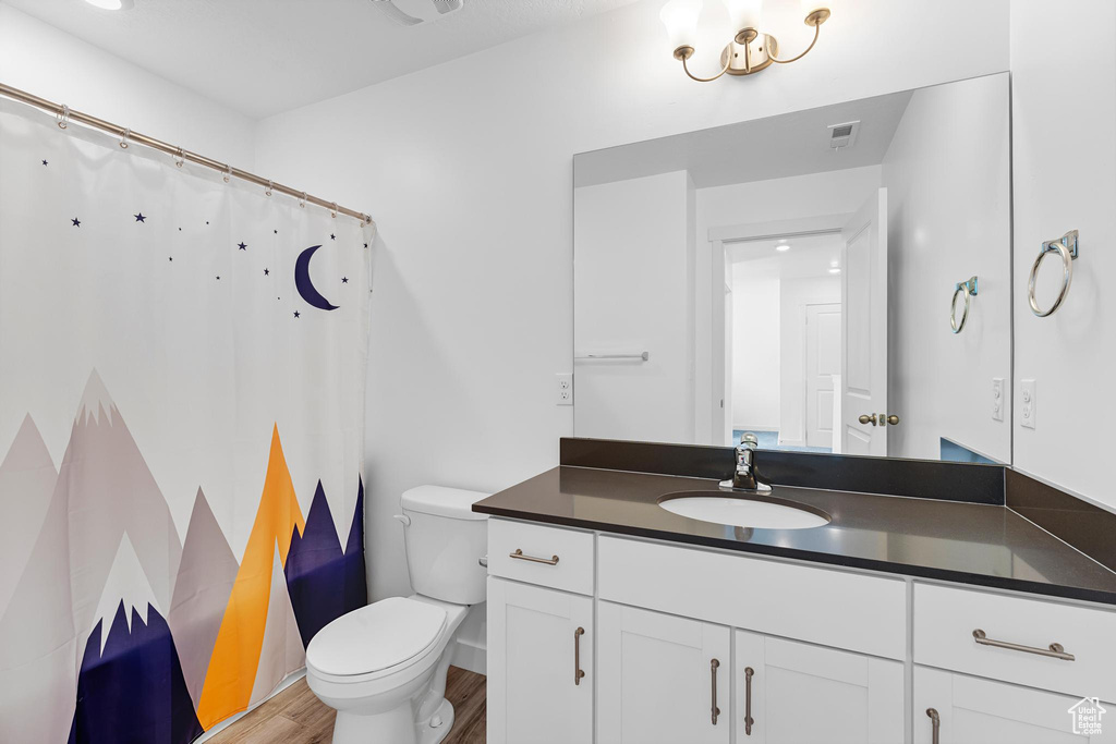 Bathroom with toilet, wood finished floors, vanity, baseboards, and a shower with curtain