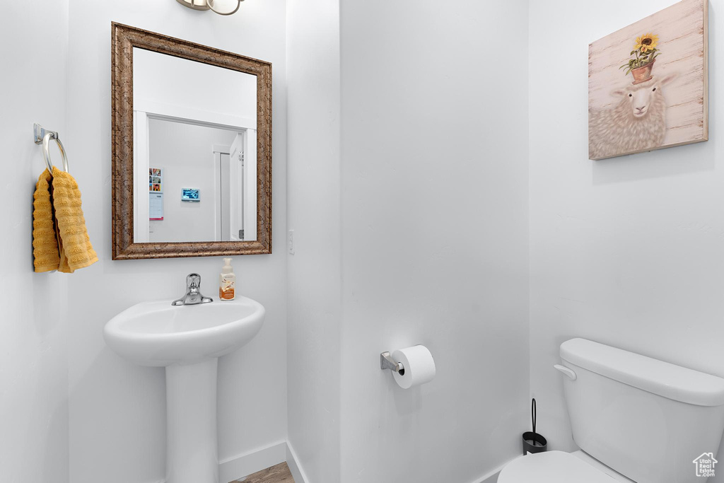 Half bathroom featuring toilet, baseboards, and a sink