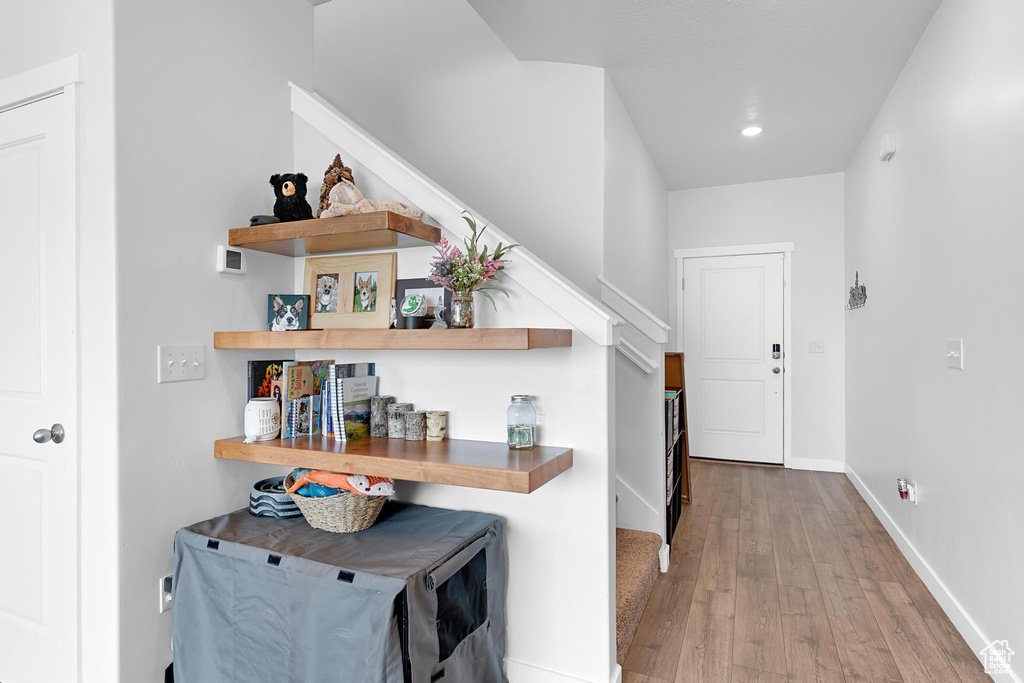 Hallway featuring wood finished floors, stairway, recessed lighting, and baseboards