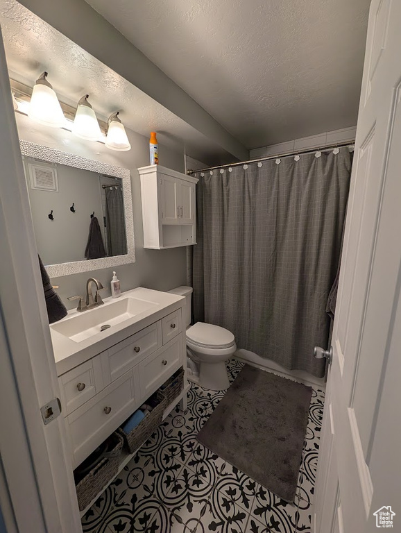 Full bath with toilet, vanity, a shower with shower curtain, tile patterned flooring, and a textured ceiling