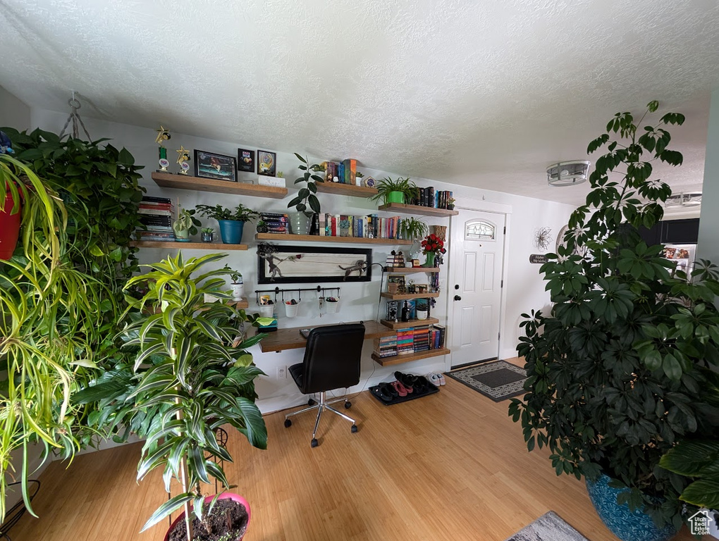 Home office with wood finished floors, a textured ceiling, and built in desk