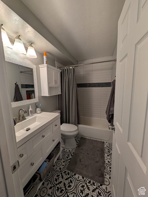 Bathroom with toilet, vanity, shower / tub combo, tile patterned floors, and a textured ceiling