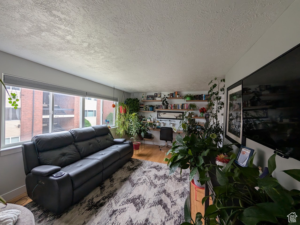 Living room featuring a textured ceiling, light wood-style floors, and baseboards