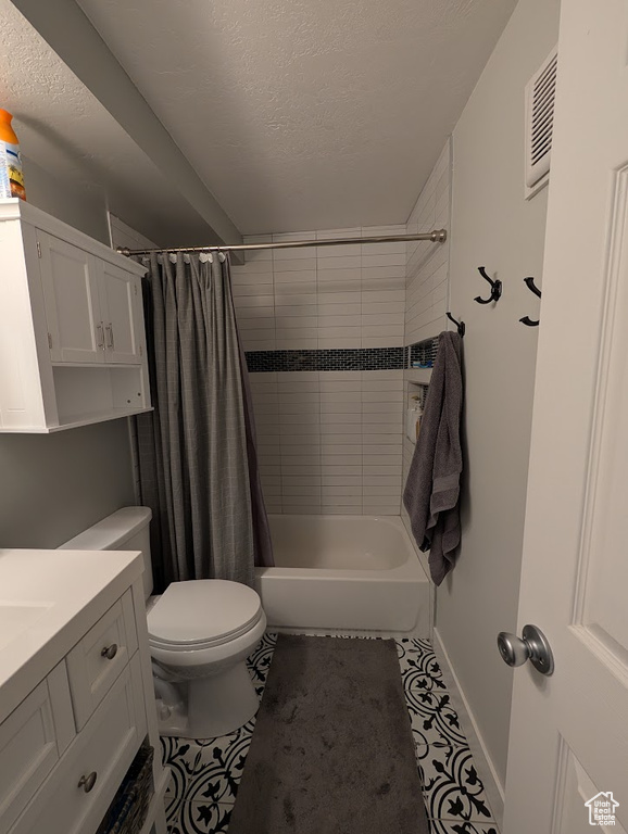 Full bathroom with toilet, shower / tub combo, tile patterned flooring, vanity, and a textured ceiling