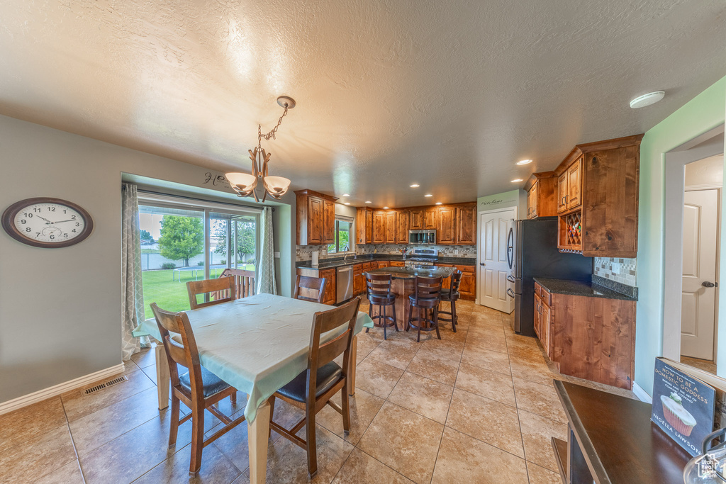Dining space with recessed lighting, a chandelier, baseboards, a textured ceiling, and light tile patterned floors