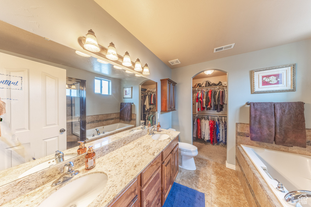 Bathroom with a garden tub, double vanity, a walk in closet, tile patterned flooring, and toilet