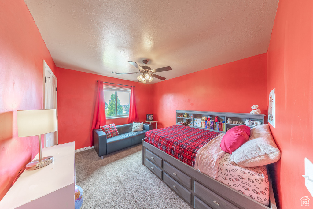 Carpeted bedroom featuring a textured ceiling, a ceiling fan, and baseboards