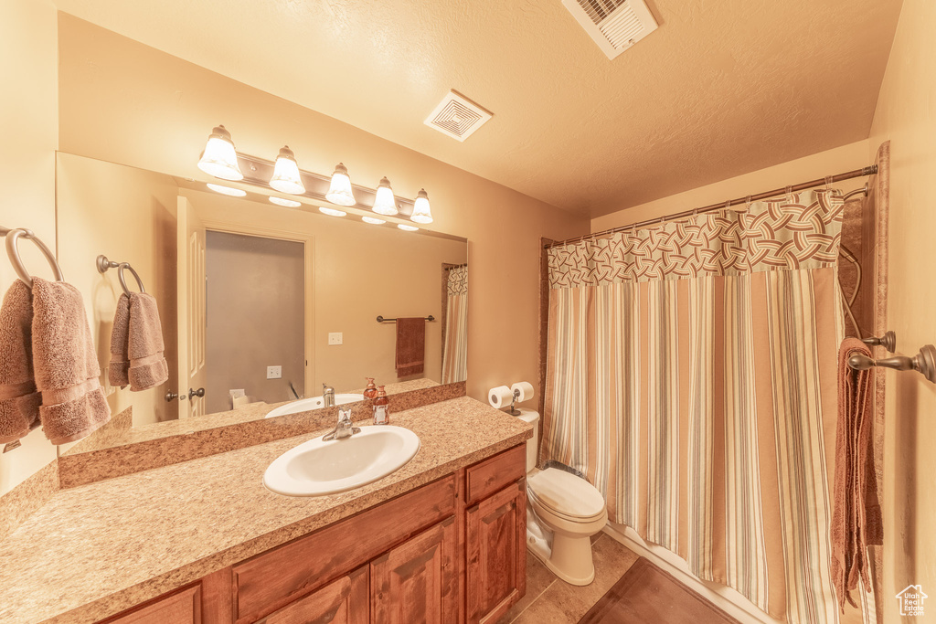 Full bathroom featuring toilet, tile patterned flooring, vanity, and curtained shower