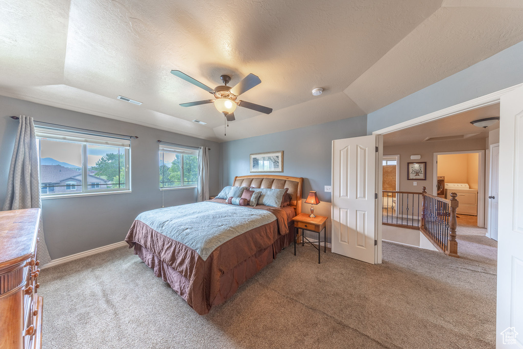 Bedroom featuring carpet floors, baseboards, washer / dryer, a raised ceiling, and ceiling fan
