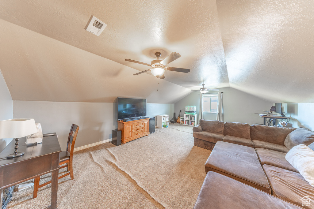 Living area with light carpet, ceiling fan, a textured ceiling, vaulted ceiling, and a desk