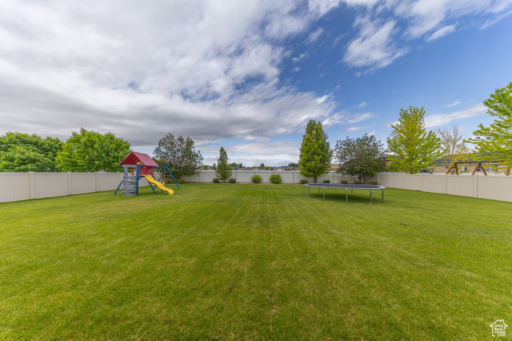 View of yard with a trampoline and a playground