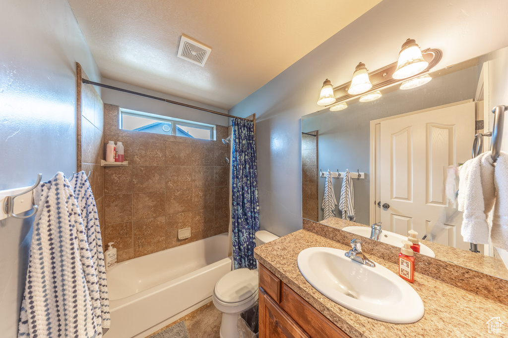 Bathroom with toilet, shower / bath combo, and vanity