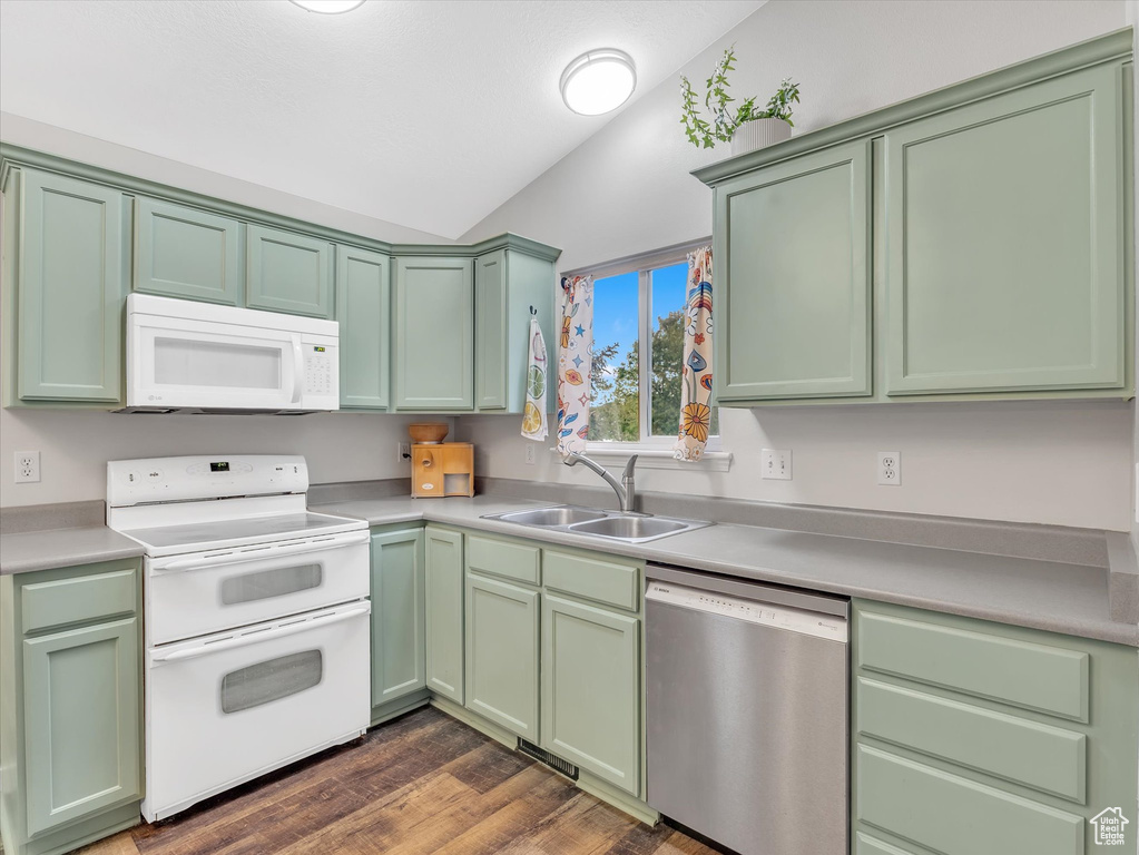Kitchen featuring white appliances, green cabinetry, vaulted ceiling, a sink, and light countertops
