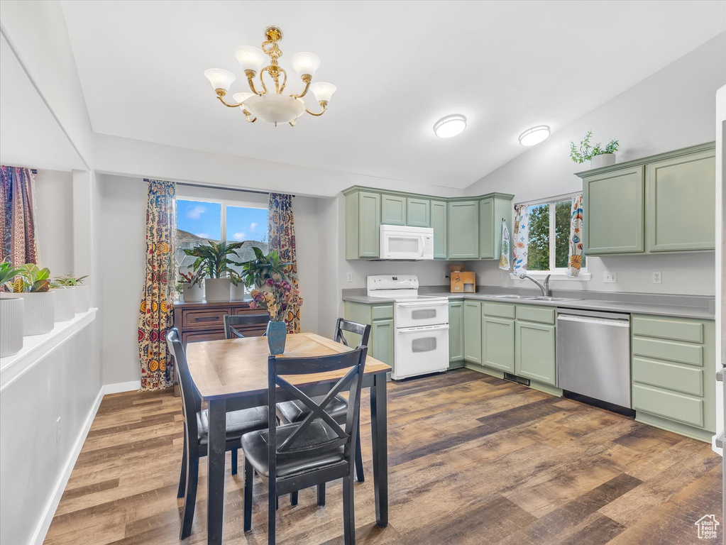 Kitchen featuring white appliances, green cabinetry, a chandelier, dark wood-style floors, and lofted ceiling