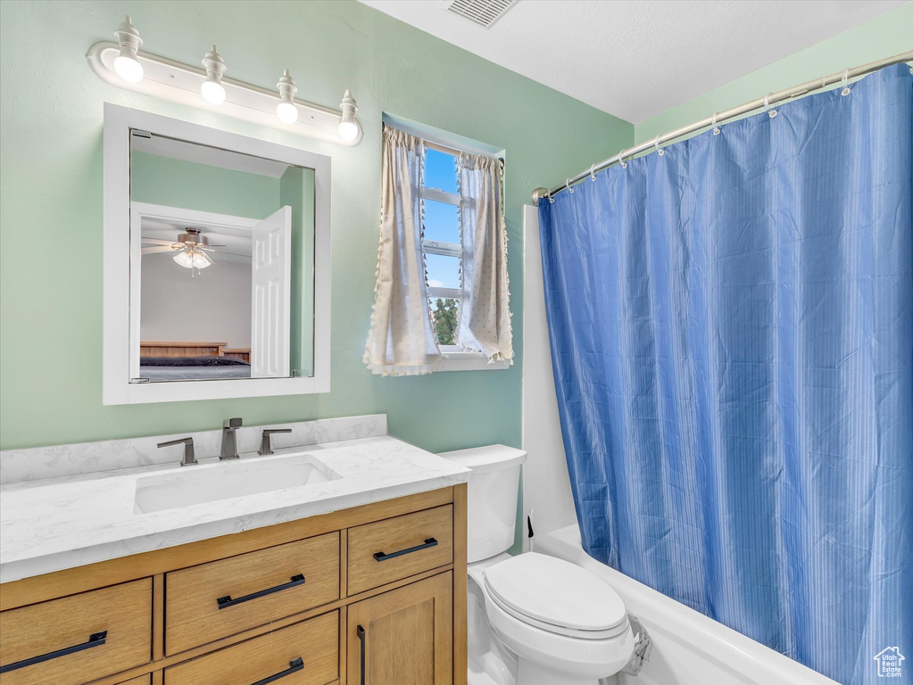 Bathroom with toilet, vanity, and shower / bath combo with shower curtain