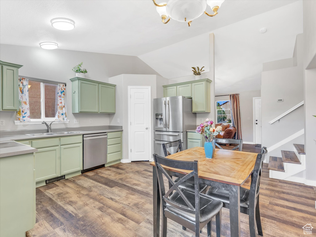 Kitchen with green cabinetry, stainless steel appliances, and lofted ceiling