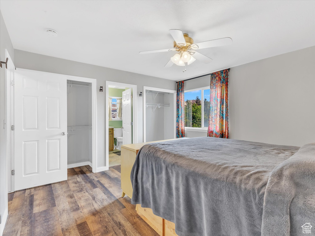 Bedroom featuring wood finished floors, a ceiling fan, baseboards, and ensuite bath