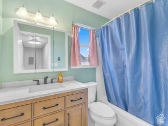 Bathroom with toilet, vanity, and shower / tub combo