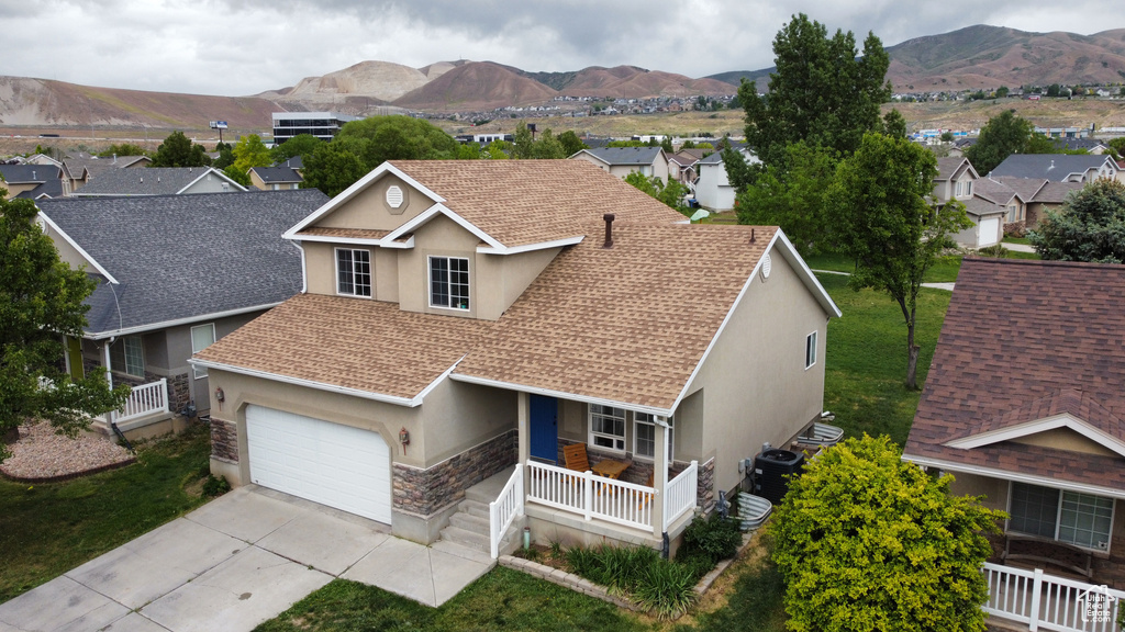 Traditional-style home with stucco siding, a porch, stone siding, roof with shingles, and concrete driveway