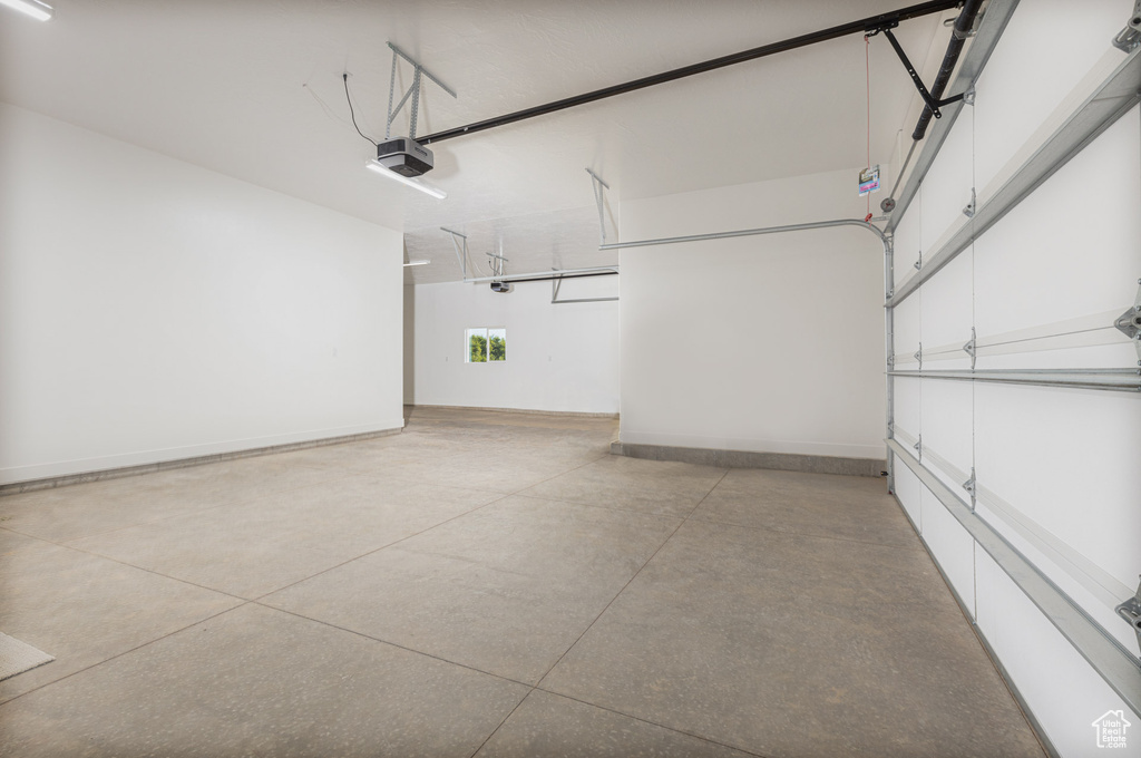Garage featuring a garage door opener and baseboards