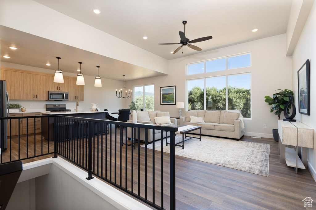 Living room with dark wood-style floors, recessed lighting, a ceiling fan, baseboards, and a chandelier