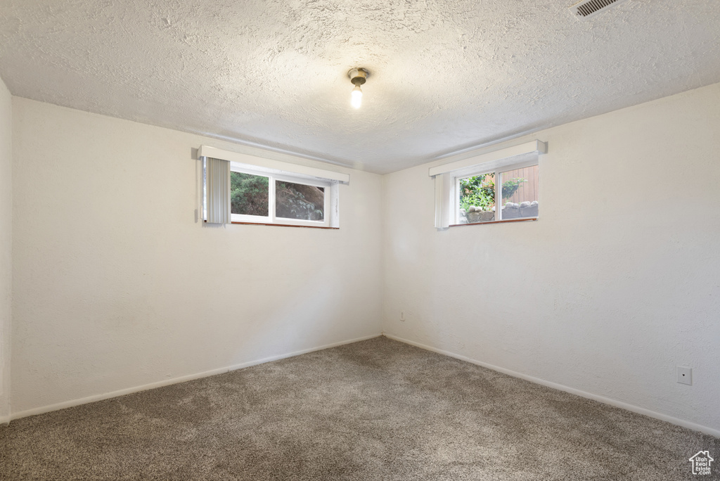 Spare room featuring carpet flooring, a textured ceiling, and baseboards